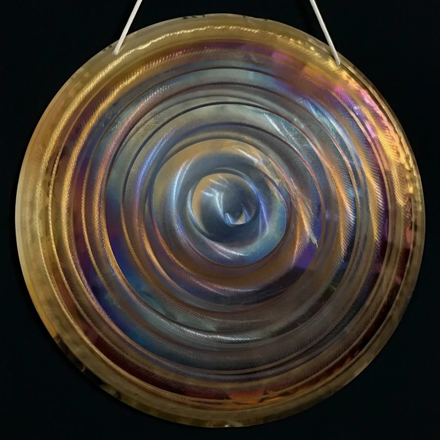 Warm gold 50 cm gong with a blue spiral at its centre, hanging on a white cord