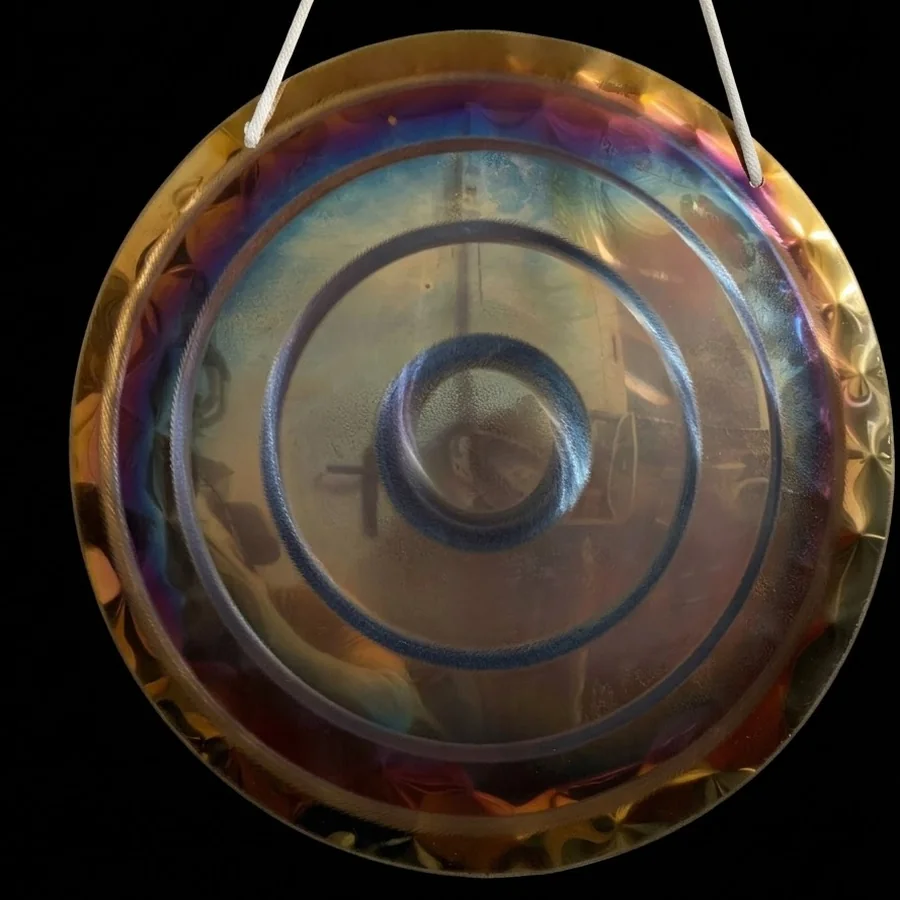 Muted gold handheld gong with two simple rings on a black background