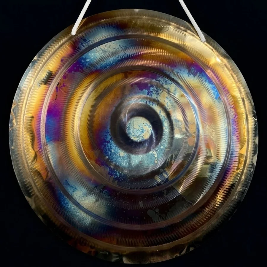 Speckled blue and gold heat patterns around the central spiral of a 50 cm stainless steel gong